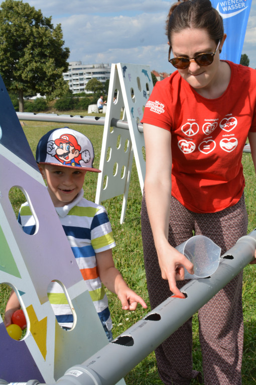 Betreuerin der Kinderfreunde und Bub beim Spielen mit Wasserrinne